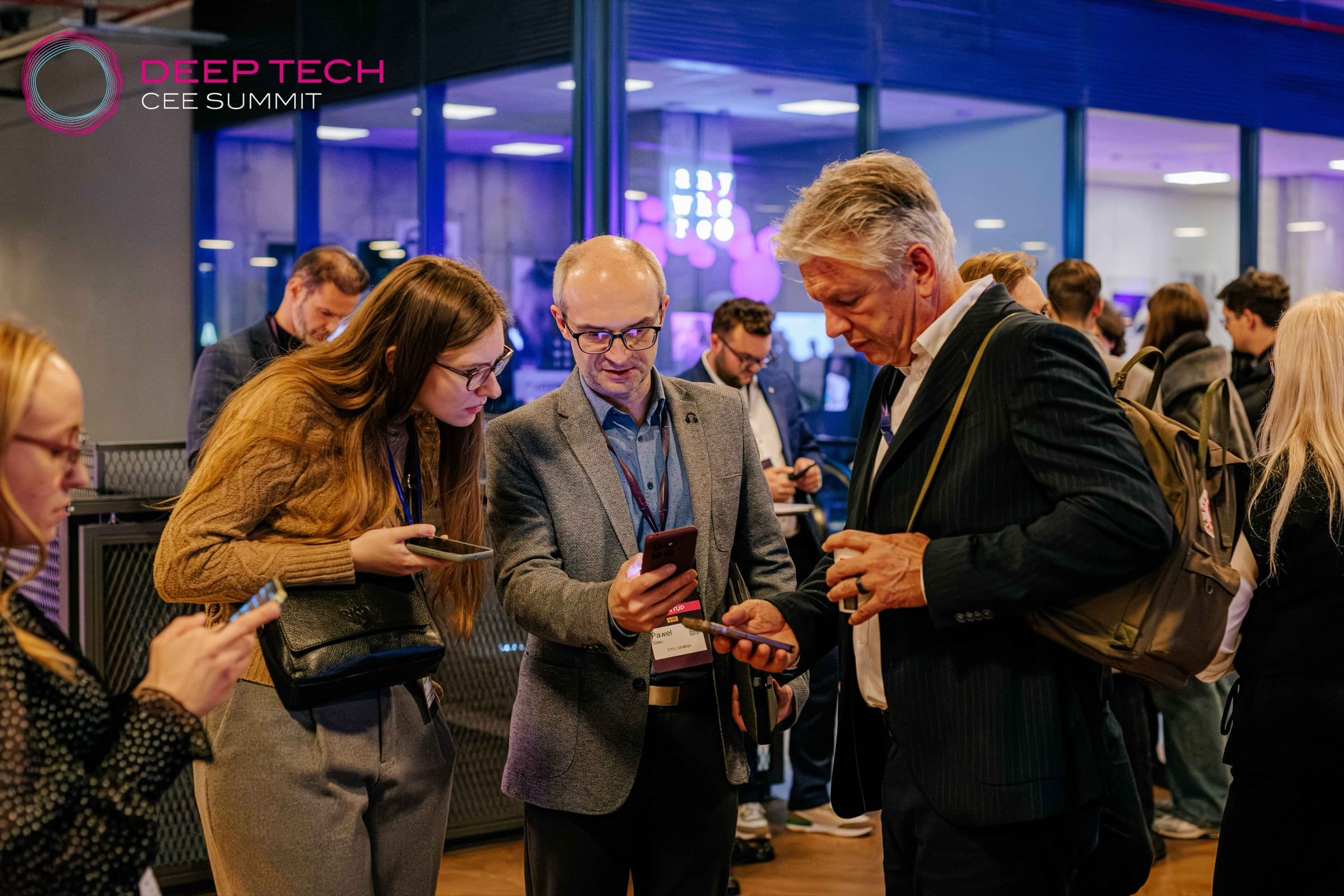 Attendees with Summit badges compare notes on their phones between sessions at Deep Tech CEE Summit 2025