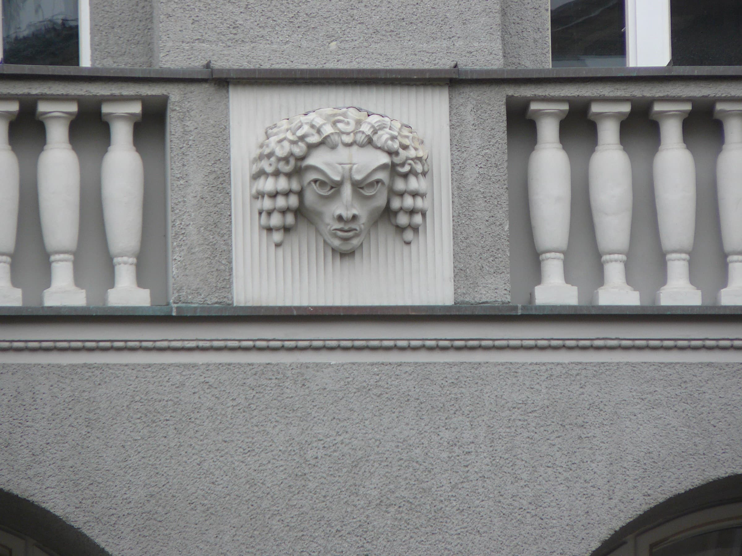 Carved mask between balustrades on the facade of Dom Towarowy Bracia Jabłkowscy
